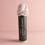Keratin shampoo bottle with towel on a pink background
