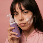 Woman holding a purple bottle with a pink background