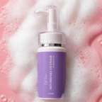 Purple skincare bottle with pump on a pink foamy background